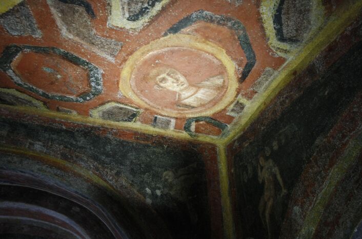 A spotlight illuminates the icon of the apostle John in a catacomb in Rome, Italy.